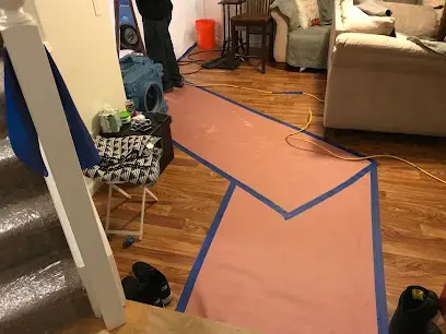 Floor protection and air movers set up in a living room during a Gresham, OR dry-out