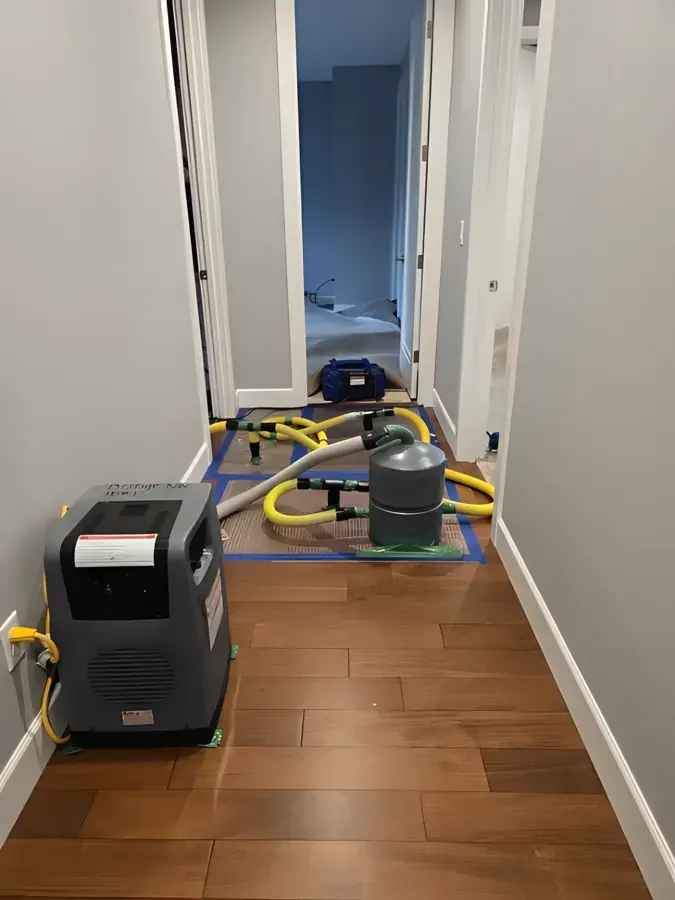 Dehumidifier and hoses drying a hallway hardwood floor in Gresham, OR